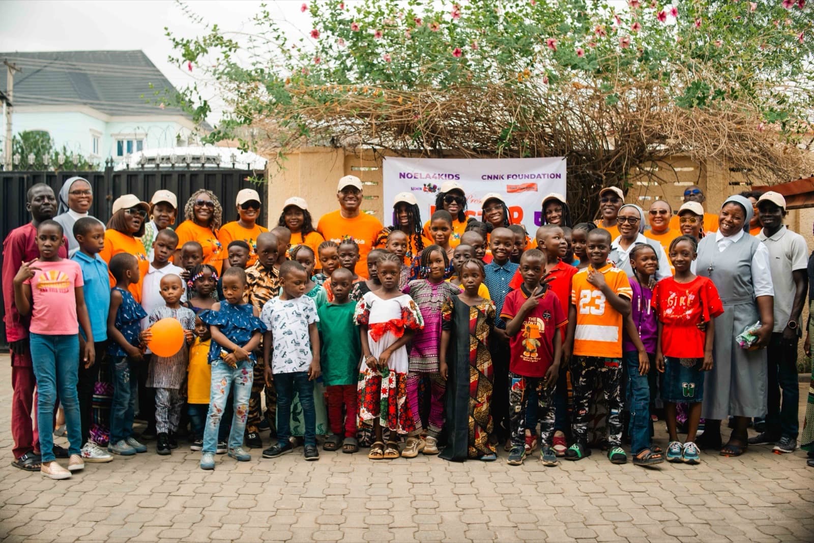 Children and volunteers gathered in front of the Noela4kids and CNNK Foundation banner