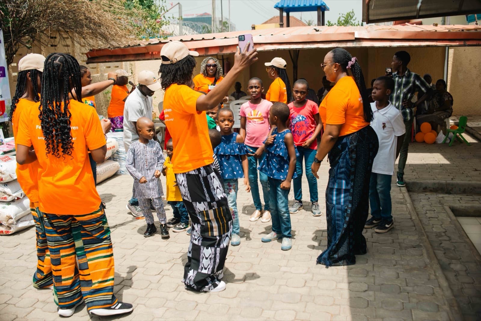 Noela4kids volunteers in orange shirts gathered with children during the Easter Outreach